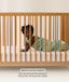 Product feature graphic showing a baby on their stomach in a green Sleeping Bag, with text explaining the side-zip feature for tummy sleepers.