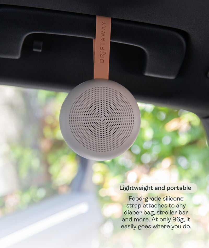 A lightweight, circular Drift Away White Nosie machine suspended by a food-grade silicone strap attached to a car handle. Text overlay titled 