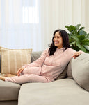 Lifestyle asset of women sitting on a couch wearing ergoPouch Adult Sleep Onesie Daisies