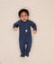 Baby lying on their back wearing a navy blue long-sleeve zip-front base layer with fold over foot cuffs, designed for a snug, comfortable fit.