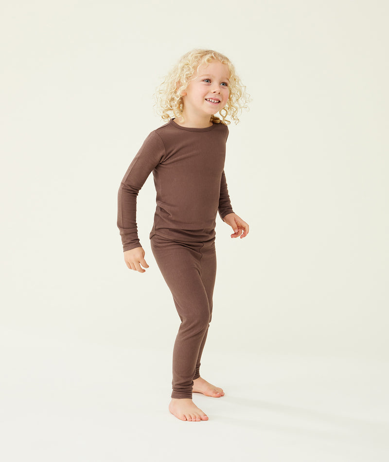 A preschooler standing against a cream background wearing a brown long sleeve pyjama set with matching pants, designed for everyday comfort.