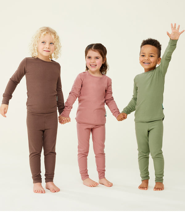 Three preschool kids wearing ergoPouch Long Sleeve Pyjamas in Cocoa, Rose, and Moss.