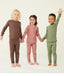 Three preschool kids wearing ergoPouch Long Sleeve Pyjamas in Cocoa, Rose, and Moss.