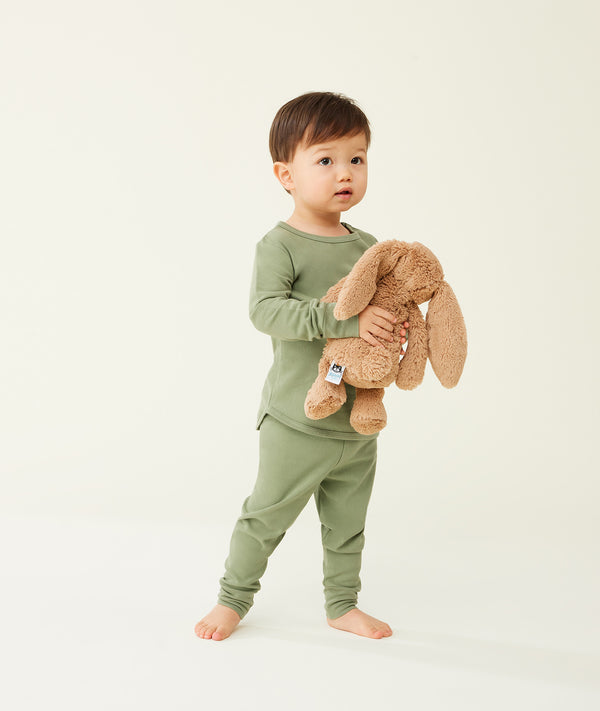 Toddler holding a plush toy wearing an olive green long-sleeve pyjama set, with match pants.