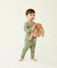 Toddler holding a plush toy wearing an olive green long-sleeve pyjama set, with match pants.