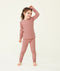 A happy little girl wearing a blush pink Long Sleeve Pyjama Set with matching pants, made from soft, comfortable fabric.
