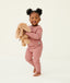Toddler holding a plush toy wearing a blush pink long-sleeve pyjama set with matching pants, made from soft, comfortable fabric.