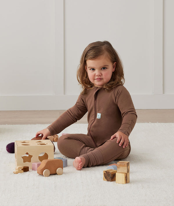 Toddler sitting on a rug while playing with wooden toys is wearing a brown Long Sleeve Layer, featuring a slim-fit design and soft, comfortable fabric.