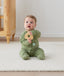 Infant sitting upright wearing an olive green Long Sleeve Layer by ergoPouch, featuring front-zip design and fold over hand and foot cuffs.