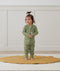 Toddler standing on a rug wearing an olive green Long Sleeve Layer by ergoPouch, made from soft, organic fabric.