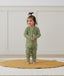 Toddler standing on a rug wearing an olive green Long Sleeve Layer by ergoPouch, made from soft, organic fabric.