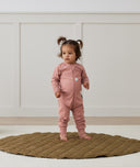 Toddler standing on a rug wearing a Long Sleeve Layer 2.0 TOG Rose, featuring front zipper and soft, breathable fabric.