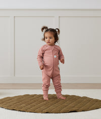 Toddler standing on a rug wearing a Long Sleeve Layer 2.0 TOG Rose, featuring front zipper and soft, breathable fabric.