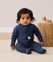 Infant sitting upright wearing a navy blue Long Sleeve Layer by ergoPouch, featuring a 3-way zip system for easy nappy changes and dressing.