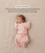 Baby lying on their back in a pink floral-patterned Cocoon Swaddle Bag with a matching Butterfly Cardi, enabling hands-up swaddled sleeping.