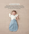 Baby in a blue dragonfly-patterned Cocoon Swaddle Bag with one arm released using a Butterfly Cardi, accompanied by text explaining how to use it as a transition tool.
