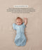 Baby in a blue patterned Cocoon Swaddle Bag with one arm released using a matching Butterfly Cardi, accompanied by text explaining how to use it as a transition tool.
