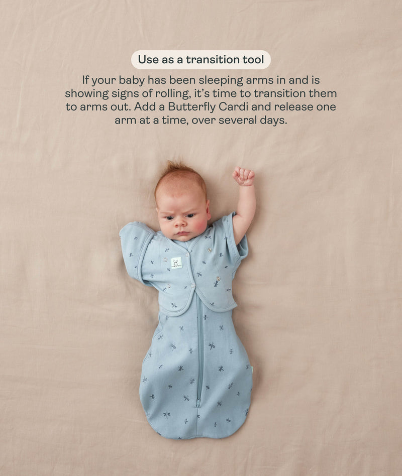 Baby in a blue patterned Cocoon Swaddle Bag with one arm released using a matching Butterfly Cardi, accompanied by text explaining how to use it as a transition tool.