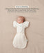 Sleeping baby lying on their back in a cream Cocoon Swaddle Bag with a matching Butterfly Cardi, enabling hands-up swaddled sleeping.