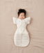 Baby lying on their back wearing a Cocoon Swaddle Bag with Butterfly Cardi over top for hands up sleeping.