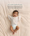 Baby in a nappy wearing a cream Butterfly Cardi, with text highlighting its use as a warm-weather swaddle alternative to help manage the startle reflex.
