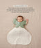 Sleeping baby in a white Cocoon Swaddle Bag with one arm released using a green Butterfly Cardi, accompanied by text explaining how to use it as a transition tool.
