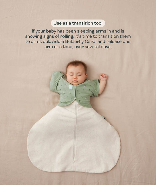 Sleeping baby in a white Cocoon Swaddle Bag with one arm released using a green Butterfly Cardi, accompanied by text explaining how to use it as a transition tool.