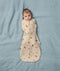 Baby lying on a soft blue sheet wearing an ergoPouch Cocoon Swaddle Bag with its arms securely swaddled inside.