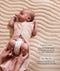 Baby lying on a textured blanket with a two-way zipper swaddle bag opened at the bottom for a nappy change, accompanied by product feature text.