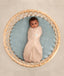 Baby snugly dressed in a Cocoon Swaddle Bag lying in a round bassinet
