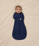 Baby is swaddled in a dark blue ergoPouch Cocoon Swaddle Bag 1.0 TOG with its arms inside.