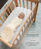 Sleeping baby swaddled inside a cream-colored patterned Cocoon Swaddle Bag in a wooden cot with text callouts highlighting swaddling benefit and TOG rating feature.