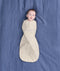 Baby lying on a blue sheet background, swaddled in an ergoPouch Cocoon Swaddle Bag 1.0 TOG Lullaby.
