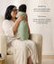 A mum sitting in an armchair holding a swaddled baby in a sage green floral Cocoon Swaddle Bag, with text callouts highlighting swaddling benefits and TOG ratings.