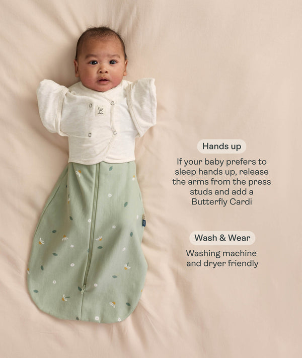Baby wearing a sage green floral Cocoon Swaddle Bag layered with a white 