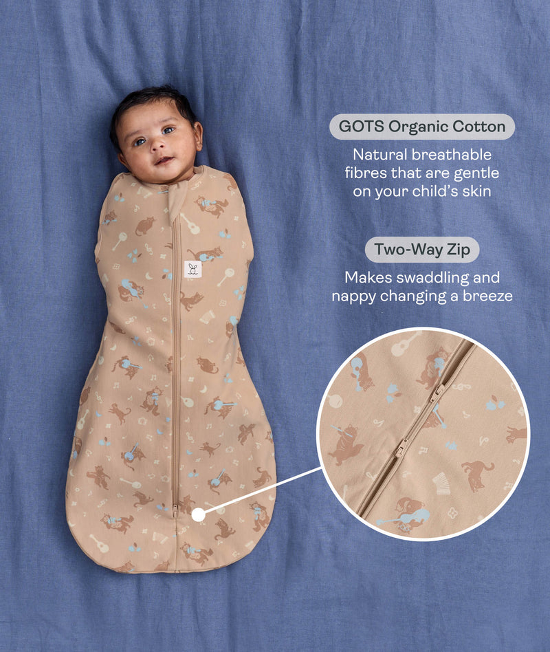 Baby lying on a blue blanket wearing a Cocoon waddle Bag with text highlighting organic cotton and two-way zip.