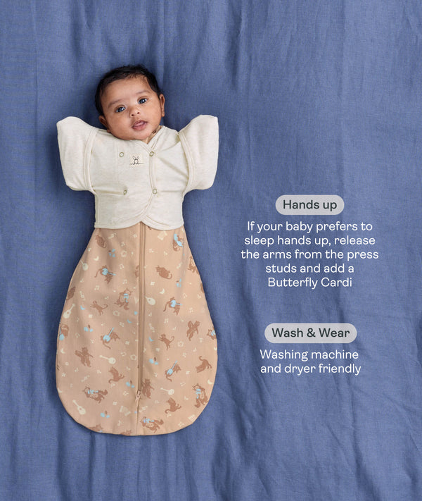 Baby wearing a Cocoon Swaddle Bag layered with a cream 
