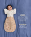 Baby wearing a Cocoon Swaddle Bag layered with a cream 
