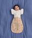 Baby lying on a blue sheet background, wearing a patterned Cocoon Swaddle Bag with a Butterfly Cardi.