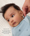 Close-up of a hand testing the neck fit of a baby's light blue dragonfly-patterned Cocoon Swaddle Bag, accompanied by instructional fit text.