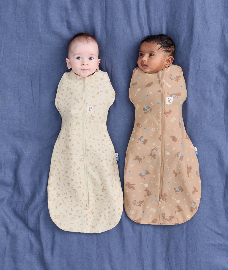 Two babies lying side by side wearing ergoPouch Cocoon Swaddle Bag 1.0 TOG in Lullaby and Melody