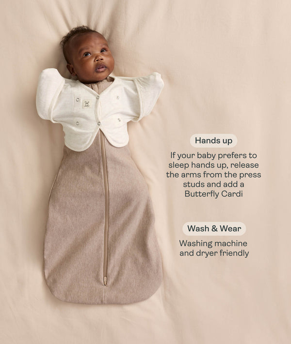 Infant wearing a Cocoon Swaddle Bag  layered with a cream 