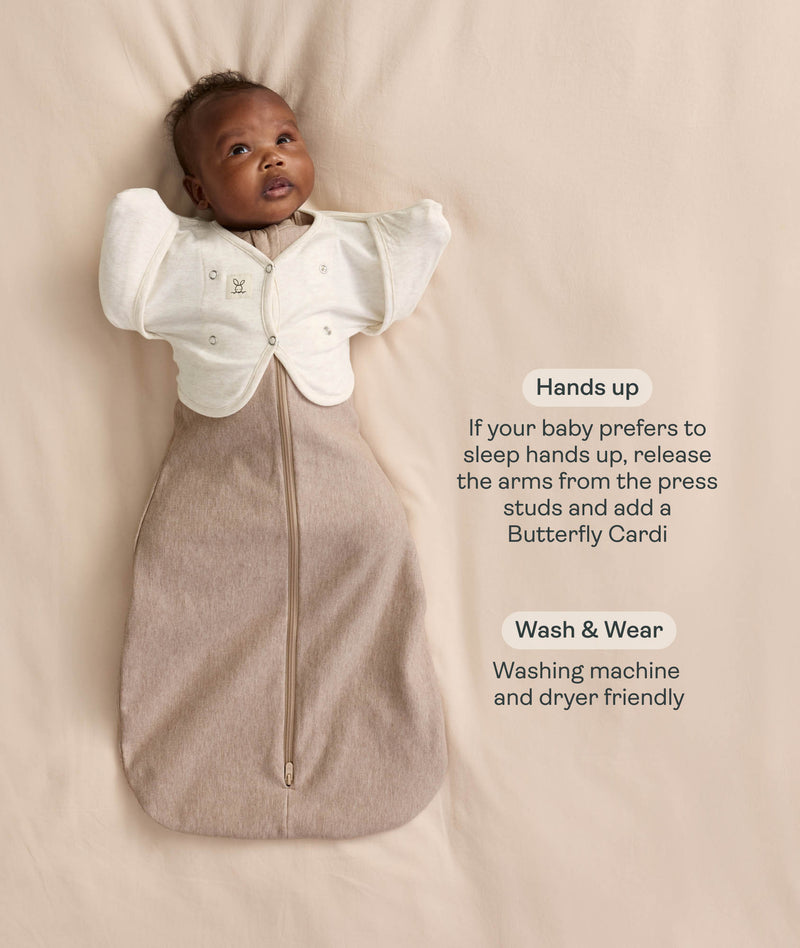 Infant wearing a Cocoon Swaddle Bag  layered with a cream 
