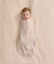 An overhead view of a baby swaddled in a patterned beige Cocoon Swaddle Bag, lying flat on a cream-colored blanket.