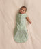 Baby wearing a sage green floral-patterned Cocoon Swaddle Bag with one arm extended out