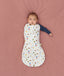 Baby lying on a pink surface snugly dressed in a 2.5 TOG Cocoon Swaddle Bag with one arm out