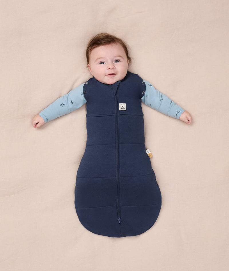 Baby dressed in an ergoPouch Cocoon Swaddle Bag 2.5 TOG with both arms outside.