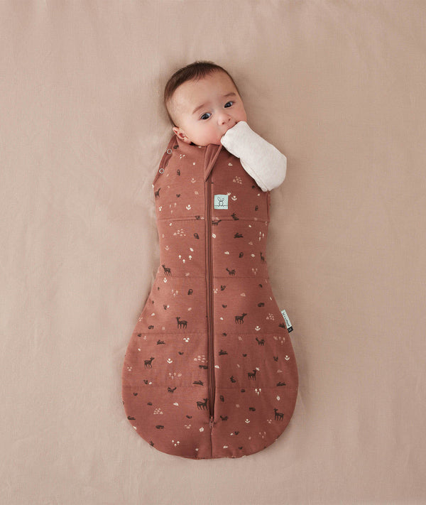 Baby is snugly wrapped in a Cocoon Swaddle Bag with its one arm out