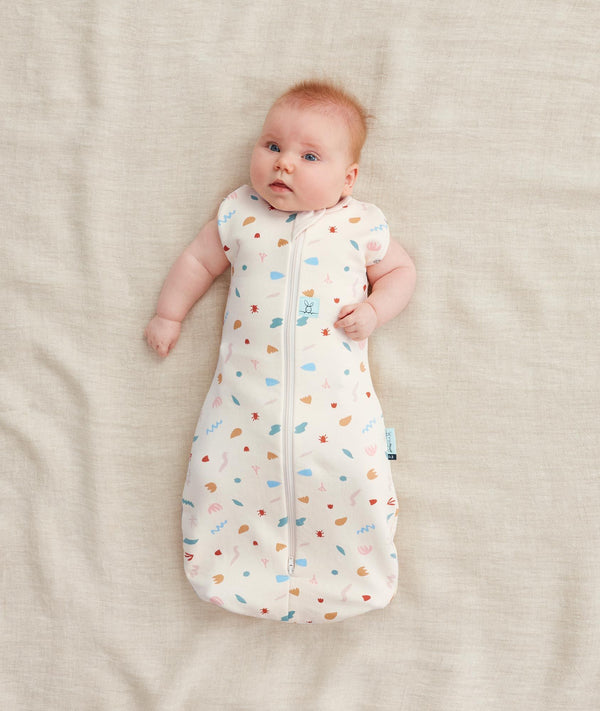 Baby wearing a 0.2 TOG Cocoon Swaddle Bag with its arms out
