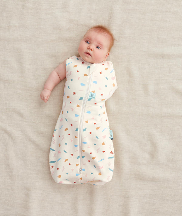 Baby wearing a  0.2 TOG Cocoon Swaddle Bag with its one arm out